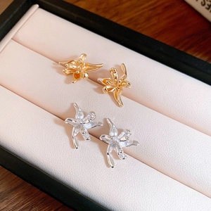 Detailed close-up of gold and silver metallic flower stud earrings in a jewelry box