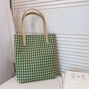 Détail du sac cabas à carreaux verts avec poignées en cuir marron et rivets métalliques