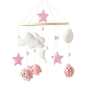 Close-up of baby mobile with wooden rings, pink stars, felt sheep and white clouds
