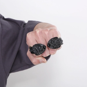 Macro shot of two bold black lion head rings with detailed matte metal relief for men