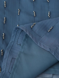 Detailed close-up of dark blue chiffon fabric with vertical silver beadwork and stitching
