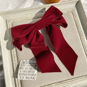 Detailed texture of burgundy velvet bridal bow clip on vintage wooden background