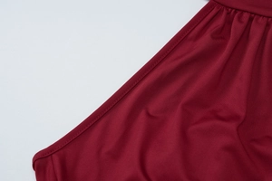 Detailed close-up of dark wine red fabric with precise double stitching and woven texture