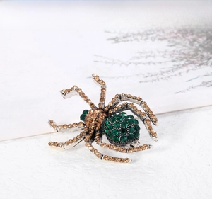 Detail of vintage spider brooch with deep green rhinestones and champagne crystals