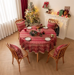 Detailed view of red Christmas deer tablecloth and matching pillows in a festive home setting