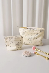 Detailed set of two beige makeup bags with black bow and polka dot patterns