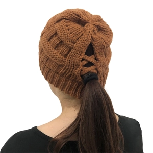 Macro detail of caramel brown knit ponytail beanie with criss-cross back opening design