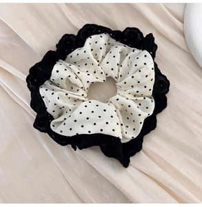 Close-up of black and white polka dot hair scrunchie with delicate lace trim detail
