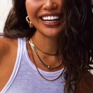Gros plan d'un collier chaîne serpent dorée avec boucle T et boucles d'oreilles torsadées