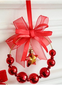 Dettaglio di una ghirlanda di Natale rossa con grande fiocco, perline e stella glitter