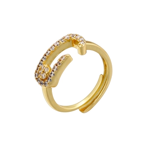 Macro detail of golden safety pin ring featuring shimmering white zircon stones on a white base