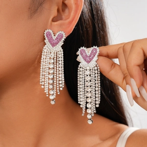 Close-up of pink heart tassel earrings with silver rhinestones worn by a model