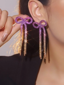 Detail of elegant bow tassel earrings with sparkling rhinestones in gradient pink and gold