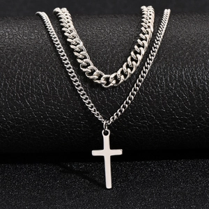Double-layered silver Cuban chain necklace with cross pendant on black background