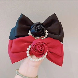 Detail of red and black satin bow hair clips with silk roses and pearl center accents