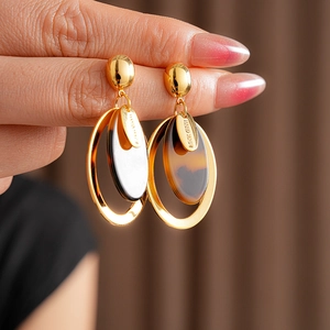 Detail of handmade oval resin earrings with gold plating and tortoise texture