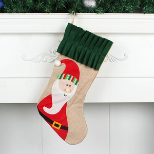 Rustic burlap Christmas stocking with 3D Santa applique hanging on a fireplace
