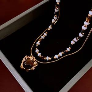 Double-layered gold necklace with heart-shaped tiger eye stone in black velvet jewelry box