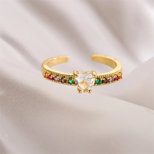 Detailed close-up of heart-shaped gold ring with zircon stones on silk background