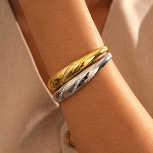 Detailed view of 18k gold and silver plated twisted bangles with inlaid zircons on wrist