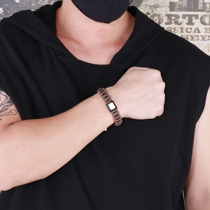Close-up of men's braided leather bracelet in black and brown with matte steel clasp