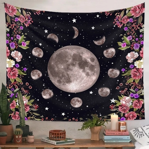 Tentures bohèmes phases de lune noires et roses rouges sur mur blanc au-dessus d'une table