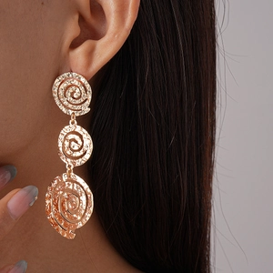 Gros plan de boucles d'oreilles dorées avec trois cercles métalliques spirale sur un mannequin