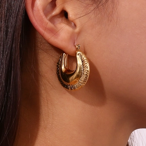 Fashionable 18K gold-plated irregular textured hollow hoop earrings worn by a model