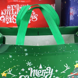 Close-up of durable reinforced green handle and festive printing on Christmas gift bag