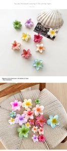 Detail of gradient plumeria hair claws in various summer colors and sizes on a beach setup