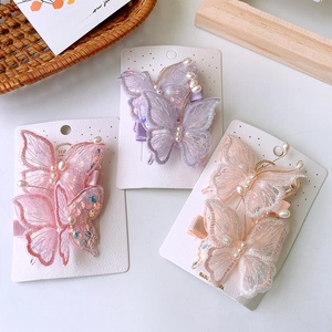 Dettaglio di fermagli per capelli a farfalla in tulle con paillettes e perle su carta
