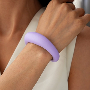 Nahaufnahme eines dicken lavendelfarbenen Acryl-Armreifs mit mattem Finish am Handgelenk