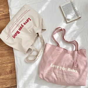 Detail of beige and pink canvas tote bags featuring Love you Baby print and long straps