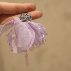 Vista de detalle de pendientes de flores de gasa lila con circonitas elegantes
