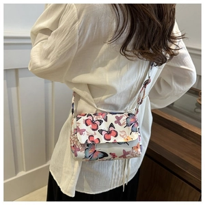 Detail of white butterfly print crossbody bag featuring a flap closure and slim shoulder strap