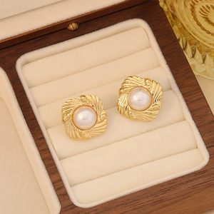 Macro detail of gold vintage heart-shaped pearl earrings on a luxury velvet jewelry box