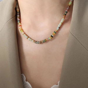 Handmade necklace with colorful translucent beads and gold spacers on model neck