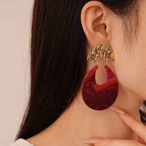 Dettaglio di modella con orecchini a forma di U in resina rossa effetto marmo