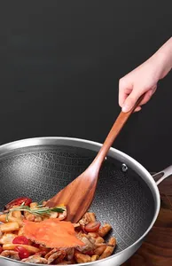 Ebony wood spatula and honeycombed stainless steel pan with stir-fried seafood