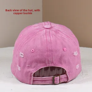 Close-up of pink washed denim baseball cap featuring distressed holes and brass buckle