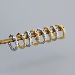 Macro shot of gold and silver huggie earrings with various cubic zirconia shapes