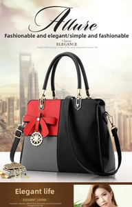 Detail of color-block handbag showing lychee pattern texture and red bow pendant