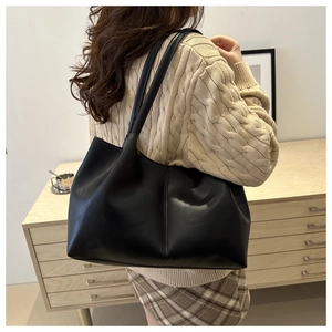 Close-up of black leather tote bag with elegant vertical stitching and slim straps