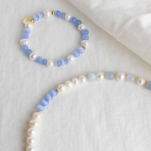 Detailed flat lay of blue cat eye stone necklace and bracelet with heart pendant