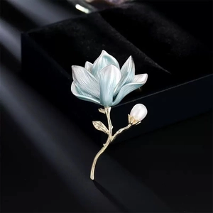Elegant magnolia flower brooch with light blue enamel petals and a white pearl on gold base