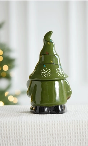 Close-up of ceramic gnome Christmas tree candy jar with snowflake pattern on a festive table
