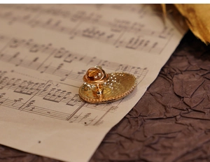 Detailed back view of vintage golden oval brooch showing secure pin fastener on music sheet