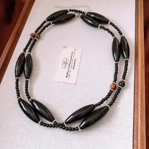 Ethnic style long beaded necklace with tiger eye stone and black spindle beads in a tray
