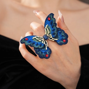 Detailed close-up of a vintage butterfly ring with blue embroidery and colorful rhinestones
