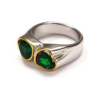 Detail of a wide polished steel ring featuring two heart-shaped green gemstones